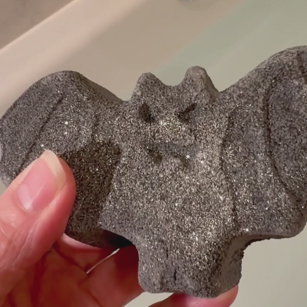 a black bat bath bomb dissolving in the bath